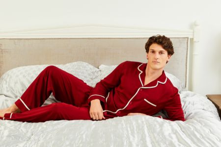 Person wearing red pajamas sitting on a bed in a well-lit room